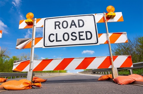Orange and white barricade with black/white sign that reads: Road Closed